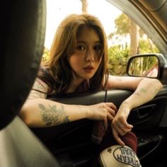 a woman sitting in the back seat of a car with her foot on the steering wheel