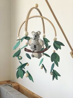 a mobile with a koala bear hanging from it's side and green leaves