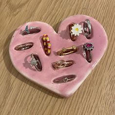 a pink heart shaped tray filled with lots of rings