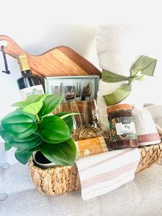 a basket filled with items sitting on top of a couch next to a potted plant