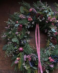 a christmas wreath with pink ribbon on a wooden table