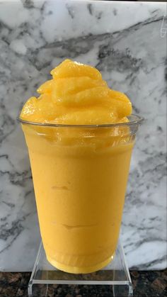 a glass cup filled with yellow liquid on top of a marble counter