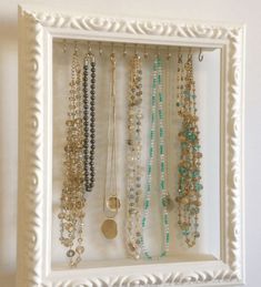 a white frame holds several necklaces and bracelets on display in a jewelry holder