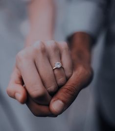 a close up of a person holding the hand of another person with a ring on their finger