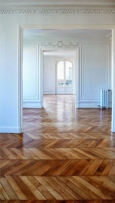 an empty room with white walls and wood floors