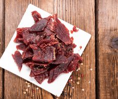 raw beef chunks on a white plate with seasoning sprinkled around the edges