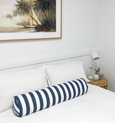 a white bed with blue and white striped pillows