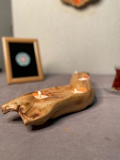 a wooden candle holder sitting on top of a bed next to two framed pictures and candles