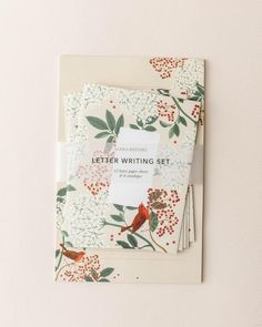 the letter writing set is laid out on top of a white envelope with red flowers