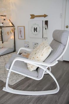 a rocking chair with a pillow on top of it in front of a white wall