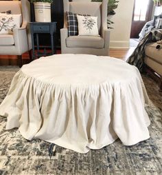 a living room with couches, chairs and a round table covered in a white skirt