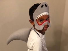 a young boy wearing a shark mask and white shirt