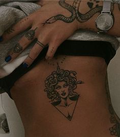 a woman with tattoos on her stomach holding a cell phone