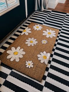 a door mat with daisies on it in front of a black and white checkered floor