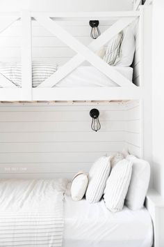 a bunk bed with white sheets and pillows