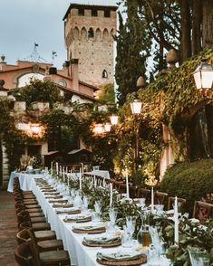 a long table is set with place settings for an outdoor dinner in front of a castle