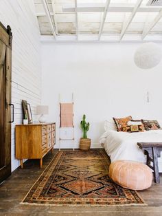 a bedroom with a bed, dresser and rug on the floor in front of it