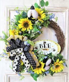 a wreath with sunflowers and polka dot ribbon hangs on the front door frame