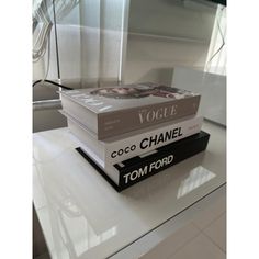 three books stacked on top of each other in front of a glass table with white curtains