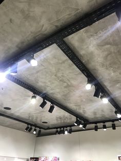 some lights are hanging from the ceiling in a room with white walls and concrete flooring