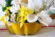 a yellow vase filled with white and yellow flowers