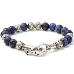 This piece is a unique blend of two exceptional materials. One is Sterling Silver that the master craftsman John Varvatos often uses to elevate the design of metal features and add a layer of luxury to the piece. The other is Sodalite. He uses this rare gemstone only when the item demands natural aquatic tones no other stone can match. Sodalite can be found only in a few places around the world. Only a small percentage of those qualify as jewel-worthy. And an even smaller percentage of those are Luxury Sterling Silver Beaded Bracelets, Elegant Blue Bracelets With Polished Beads, Luxury Silver Bracelets With Gemstone Beads, Luxury Blue Sterling Silver Bracelet, Artisan Blue Gemstone Beaded Bracelets, Luxury Silver Beaded Bracelets With Gemstone, Luxury Blue Gemstone Sterling Silver Bracelet, Elegant Lapis Lazuli Gemstone Bracelets, Elegant Handmade Lapis Lazuli Bracelets