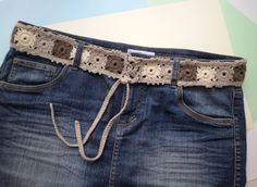 a pair of jeans with a crochet belt attached to the waist, on a colorful background