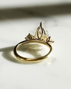 a gold ring with two pear shaped diamonds sitting on top of it's side