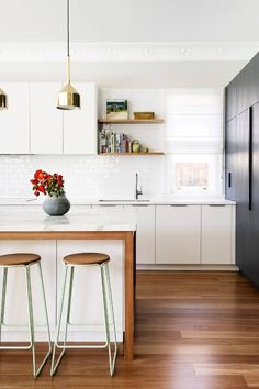 a kitchen with two stools next to a counter top and an island in the middle