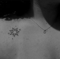 a black and white photo of a woman's chest with a sun tattoo on it