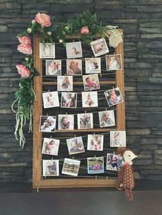 a wooden frame with pictures and flowers on it next to a stuffed animal toy in front of a stone wall