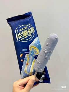 a person holding up a candy bar with an ice cream stick in it