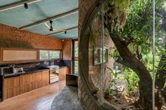 an open kitchen and dining area with trees in the back ground, surrounded by brick walls