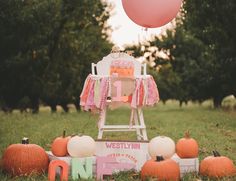 a baby's first birthday party with pumpkins, cake and balloons in the grass