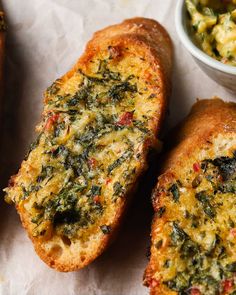 two pieces of bread with cheese and spinach on it next to a bowl of salsa