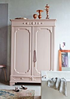 a pink armoire in a room with a rug on the floor