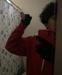 a person taking a selfie in front of a mirror with a cell phone and gloves on