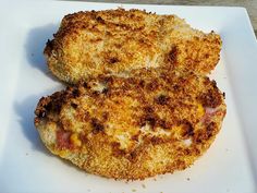 two pieces of fried chicken on a white plate with parmesan cheese and tomato sauce