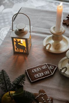 a table topped with cookies next to a lit candle and cup filled with tea lights