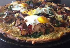 a pizza topped with mushrooms and eggs on top of a black plate sitting on a table