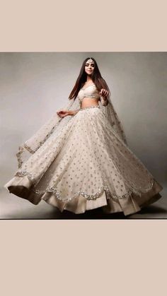 a woman in a white lehenga is standing with her hands on her hips