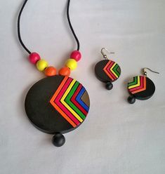 a necklace, earring and pendant made out of wood with multicolored stripes