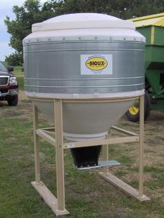 a large gray tank sitting on top of a wooden stand next to a green truck