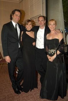 a group of people standing next to each other in formal wear and tuxedos