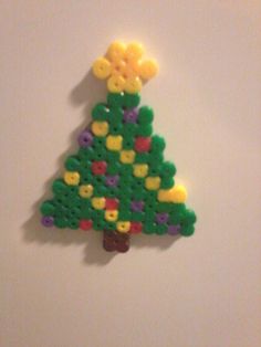 a lego christmas tree is shown on the wall in front of a white background with yellow and green decorations