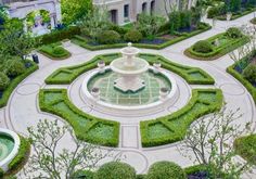 an aerial view of a garden with a fountain in the center surrounded by trees and bushes