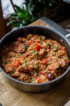 a pan filled with rice and meat on top of a wooden cutting board