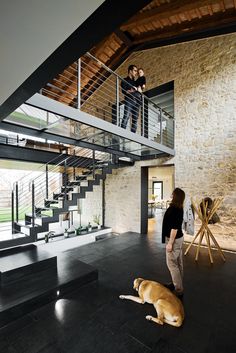 a woman standing in front of a staircase next to a brown dog on the floor