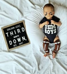 a baby laying on top of a bed next to a sign