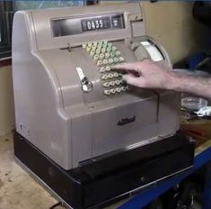 a person pressing buttons on an old fashioned cash register